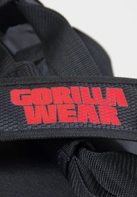 Black fabric duffel bag featuring a red "GORILLA WEAR" logo on the strap, with a textured surface and sturdy design.