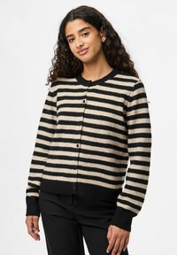 Randig kofta i svart och beige, med rund hals, knappar fram och ribbad mudd. Mjuk textur med en avslappnad passform.