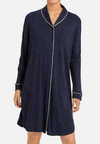 Un nightgown blu navy con bottoni, colletto a scialle, maniche lunghe e piping bianco lungo il colletto e i polsini. Tessuto morbido con una vestibilità ampia.