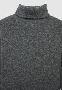 Pull à col roulé gris en tissu en maille douce. Comprend un haut col et une finition texturée avec un léger motif chiné.