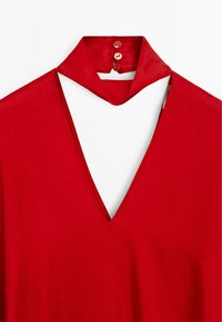 Rode jurk met een diepe V-halslijn, gestructureerde kraag en drie knopen op de achterkant. De stof lijkt glad en heeft een vloeiende val.