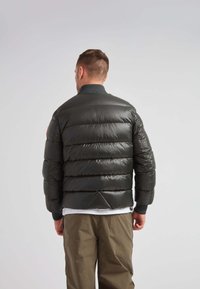 Giacca bomber imbottita di colore grigio scuro con design a righe orizzontali. Presenta collo e polsini a costine, finitura leggera e lucida, e accenti minimalisti.
