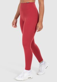 Rode legging gemaakt van rekbaar materiaal met een hoge taille. Soepele textuur, eenvoudig ontwerp en geen zichtbare patronen of hardware details.