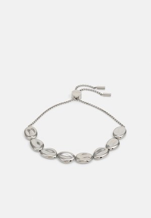 Pulsera ajustable de tono plateado con siete cuentas ovaladas lisas unidas por una cadena fina y un cierre deslizante para ajustar el tamaño.