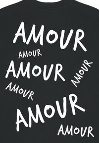 Felpa nera con la scritta "AMOUR" in vari font bianchi, dimensioni e orientamenti, creando un motivo di testo dinamico su tutta la stoffa.