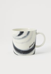 Taza de cerámica con forma curva; presenta un patrón en espiral en blanco y negro y un asa robusta; nombre de la marca impreso en negro.