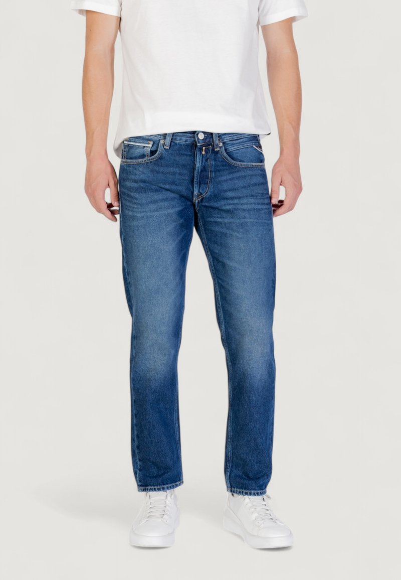 Jeans in denim azzurro chiaro con vestibilità dritta, design a cinque tasche e leggere sfumature. Abbinati a una t-shirt bianca e sneakers bianche.