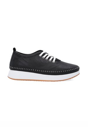 Schwarze Sneaker mit einer strukturierten Oberfläche, weißen Schnürsenkeln und Nähten. Besitzt eine dicke weiße Sohle und eine braune Gummisohle. Abgerundete Zehenform.