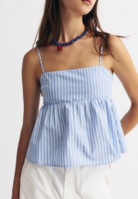 Světle modrý pruhovaný peplum top se spagetti ramínky a čtvercovým výstřihem, vyrobený z jemné látky. Doplněný o korálkový náhrdelník.
