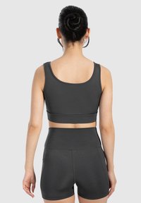 Conjunto atlético en gris oscuro que incluye un sujetador deportivo ajustado con tirantes anchos y pantalones cortos de cintura alta, fabricado con una tela suave y elástica.