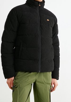 Black corduroy puffer jacket with a high collar, zip closure, and orange logo detail. Features a padded design and side pockets.