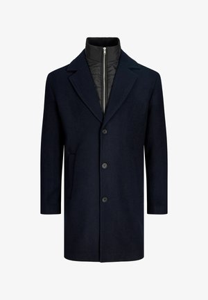 Tmavě modrý kabát z vlněné směsi s klopovým límcem, pěti knoflíky a dvěma bočními kapsami. Má prošívanou černou vnitřní podšívku a vysoký límec.