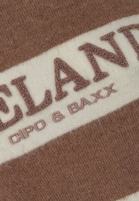 Bruin en crème gestreepte brei stof met verhoogde terry letters voor "ICELAND" en "CIPO & BAXX" in een zachte textuur.