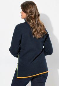 Maglione blu navy con colletto alto, caratterizzato da dettagli verdi e arancioni lungo i lati e una texture a coste all'orlo e ai polsini.