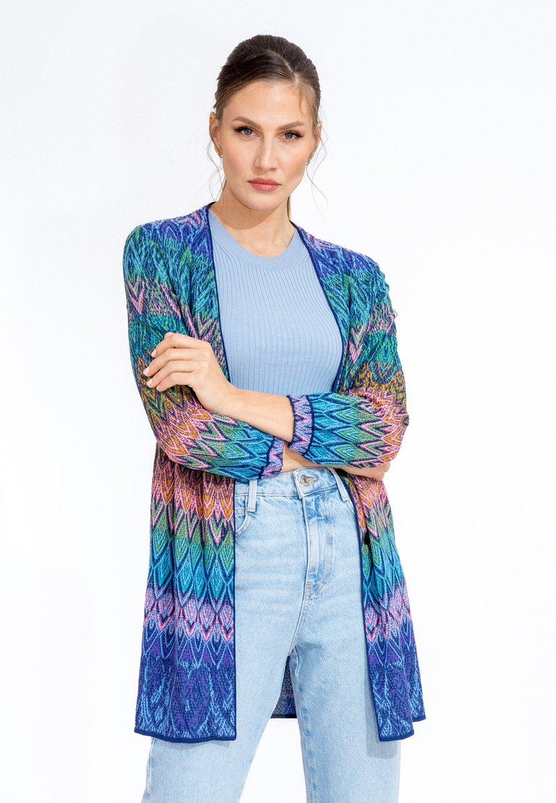 Knit cardigan with multicolored chevron pattern in blue, pink, and green. Open front, long sleeves, and a lightweight texture.