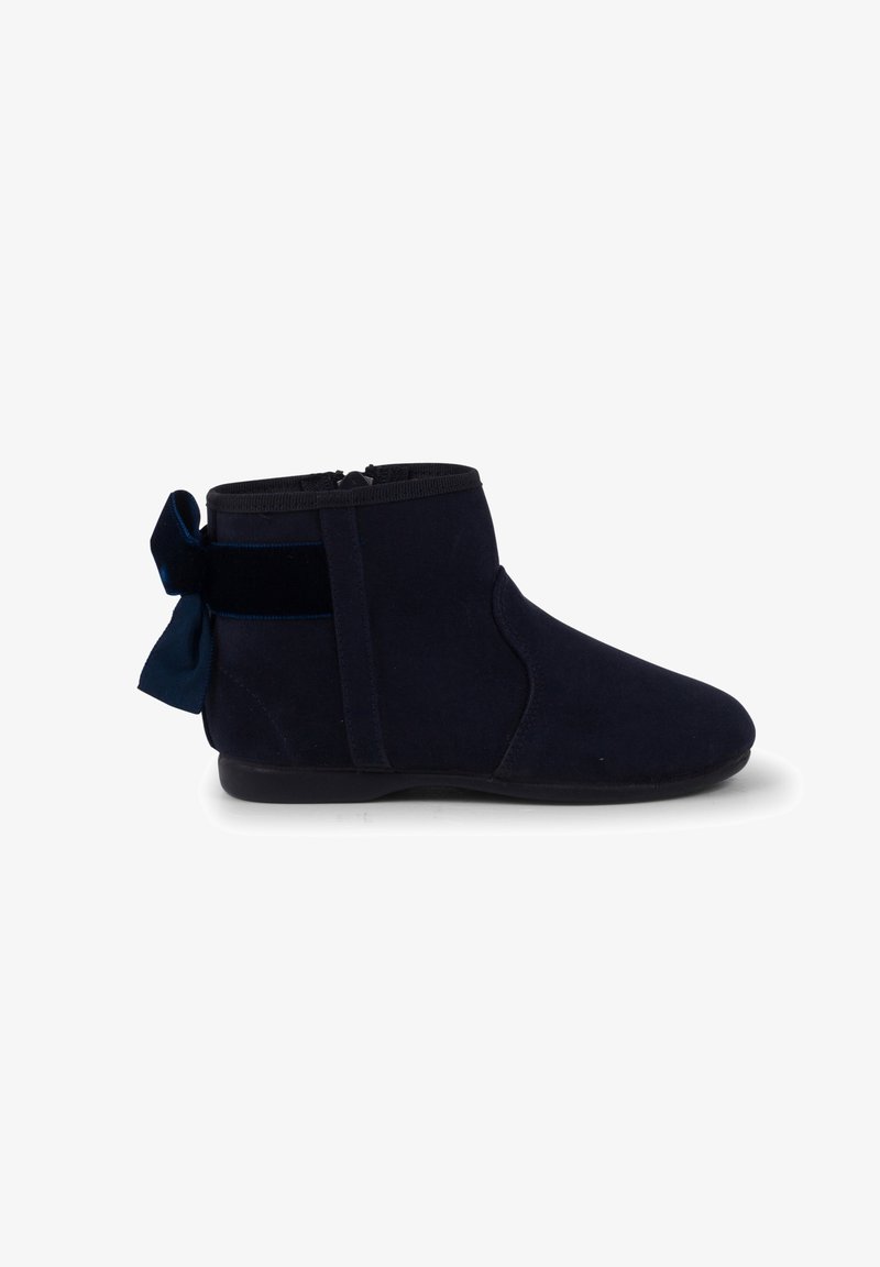 Bottes de cheville en suède bleu marine avec une fermeture éclair sur le côté et un accent en velours en forme de nœud à l'arrière. Texture douce et design à bout arrondi.