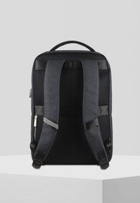 Dark gray fabric backpack with padded mesh straps, a zippered pocket on the side, and a top handle; sleek, rectangular design.