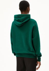 Hoodie vert en tissu doux, doté d'une grande capuche, d'une coupe décontractée, de manches tombantes et de longues manches. Texture lisse sans motifs visibles.