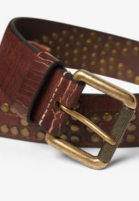 Cintura in pelle marrone con texture, dotata di una fibbia rettangolare in bronzo. Presenta borchie metalliche lungo la fascia. La vista ravvicinata mette in risalto i dettagli.
