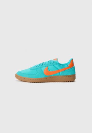 Turquoise athletic shoe with an orange Nike swoosh. Features a textured surface and a gum sole, with a padded collar and lace-up design.
