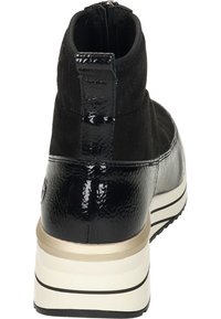 Bottine noire avec une combinaison de cuir mat et verni, un haut texturé et une semelle rayée de couleur claire avec un accent doré.