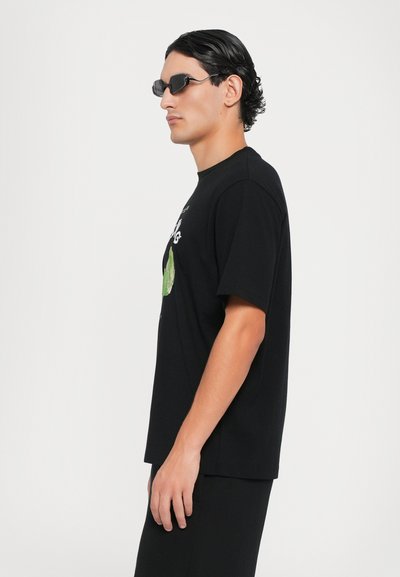 Black cotton t-shirt with short sleeves and a crew neckline, featuring a green graphic on the front. Smooth texture and relaxed fit.