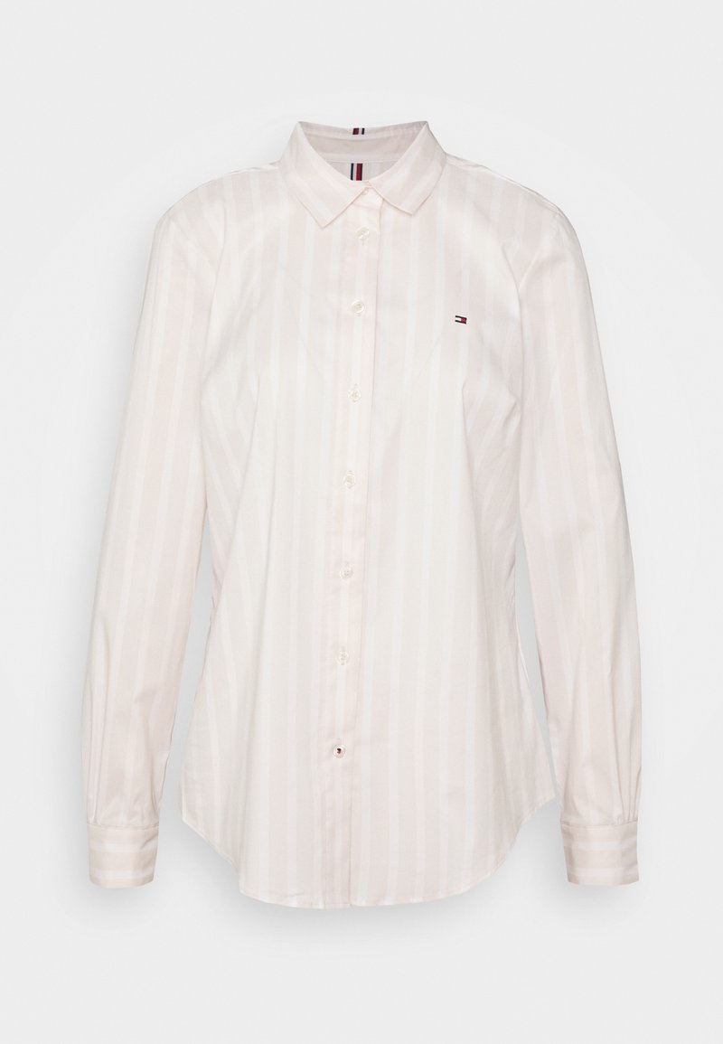 Chemise blanche à manches longues, boutonnée, avec de fines rayures verticales, un col pointu et un petit logo brodé sur la poitrine gauche.