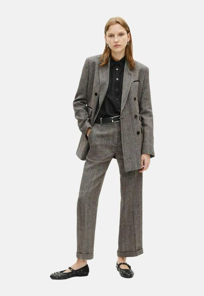 Completo grigio a quadri con blazer doppiopetto e pantaloni tapered. Abbinato a una camicia nera e ballerine nere con borchie.