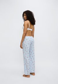 Pantalon de pyjama bleu clair avec motifs de points rouges, en tissu doux, avec une coupe ample et une ceinture élastique. Design simple, style décontracté.