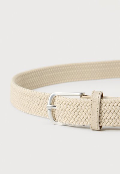Ζώνη από μπεζ υφαντό ύφασμα με ασημένιο μεταλλικό αγκράφα και δερμάτινο θηλάκι με ανάγλυφο το όνομα του бренду.