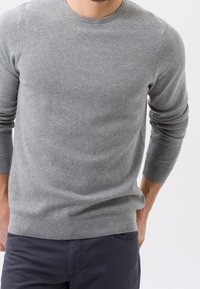 Grauer Strickpullover mit einem strukturierten Muster, rundem Halsausschnitt und langen Ärmeln, ausgestattet mit einem taillierten Saum und dezentem Markenlogo.