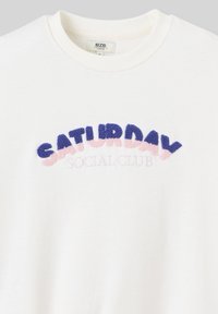 Sweatshirt blanc surdimensionné avec broderies texturées multicolores arborant l'inscription « SATURDAY SOCIAL CLUB » dans des teintes de violet et de rose.