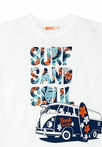 Valkoinen t-paita, jossa on graafinen suunnittelu, jossa on teksti "SURF SAND SOUL" värikkäillä kukkakirjaimilla ja kuva surf-vanista.