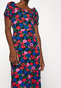 Květinové šaty s nabíranými rukávy, s černým pozadím a živými červenými, modrými a růžovými květinami. Hladká tkanina, přiléhavý střih.