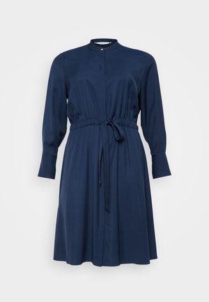 Mornarsko moder obleka, dolgi rokavi, okrogla ovratnica, zategnjen pas z vezalnim pasom, dolžina pod koleni, izdelana iz gladkega materiala z gumbnim zapenjanjem spredaj.