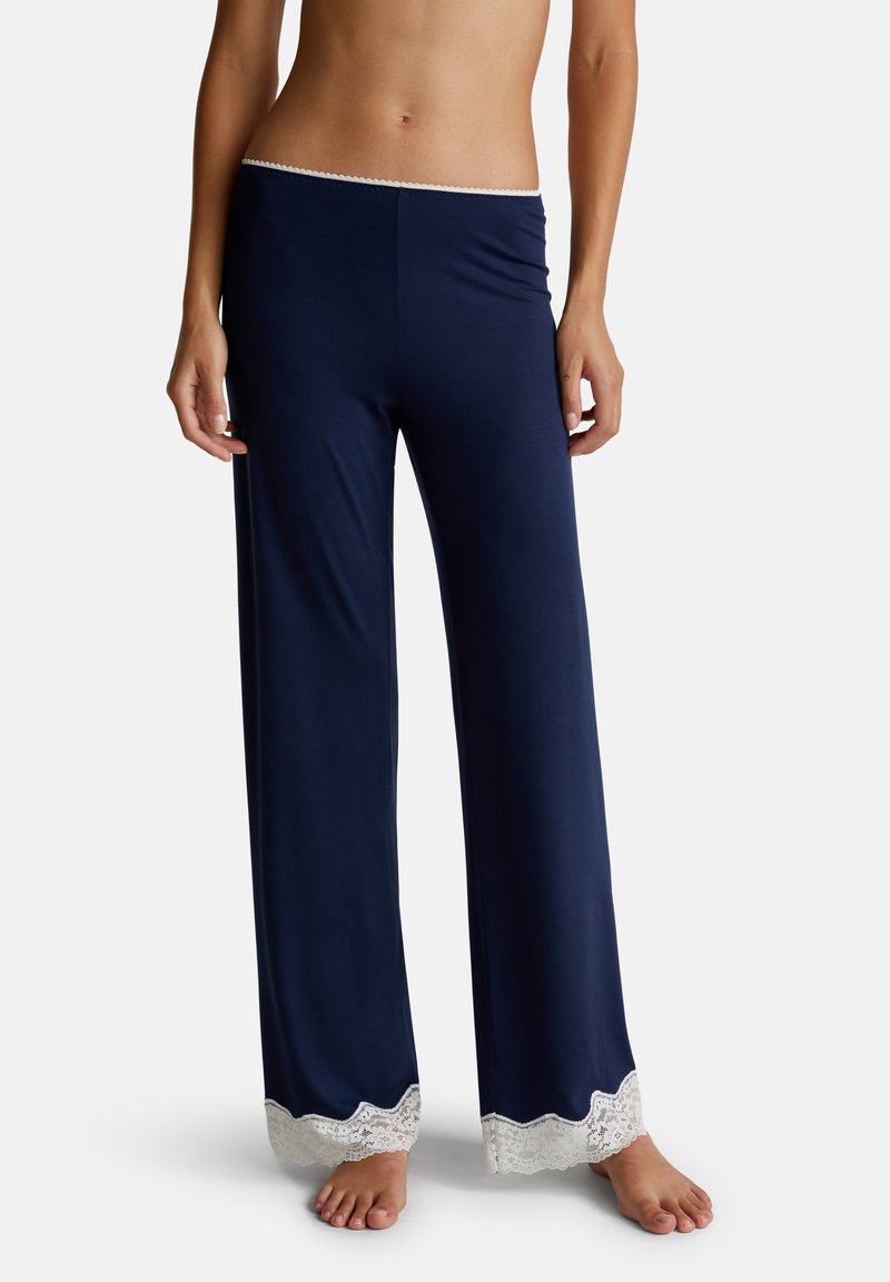 Navy loungebroek van zacht stof met een wijde pijp ontwerp, met een gegolfde witte kantafwerking aan de onderkant. Geen extra details.