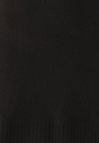 Černá svetr tkanina s měkkou texturou, která má žebrovaný lem. Materiál působí teple a hustě s konzistentním vzorem tkaní.