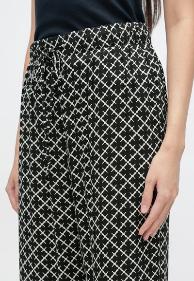 Μαύρο και άσπρο παντελόνι με μοτίβο, διαθέτει ελαστική μέση και κορδόνι. Το ύφασμα είναι ελαφρύ, με γεωμετρικό σχέδιο.