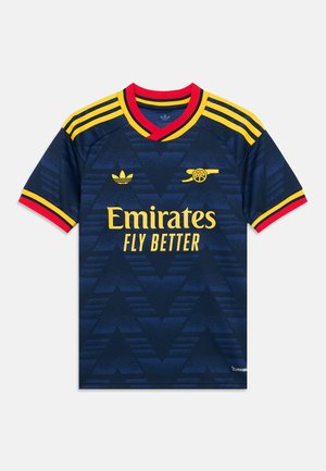 Maillot de football Arsenal bleu foncé avec bordure jaune et rouge, logo Emirates Fly Better jaune, et emblèmes Adidas et Arsenal sur la poitrine.