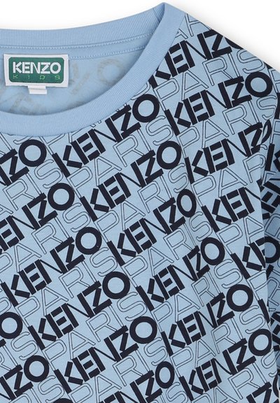 T-shirt en coton bleu clair avec un motif graphique noir répété de "KENZO" et "PARIS" de différentes tailles et orientations. Encolure côtelée.
