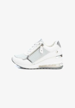 Zapatilla blanca y plateada con paneles de malla, cremallera lateral, cordones y suela con amortiguación visible de aire, mostrada desde el lado exterior.