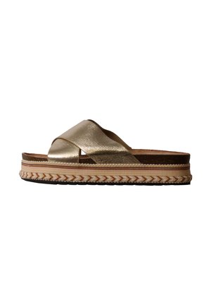 Sandale mule métallique dorée avec des brides croisées et une semelle plateforme tissée épaisse dans des tons beiges, vue de côté sur fond blanc.