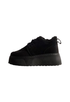 Chaussure noire à lacets, doublée de matière duveteuse, avec une bride arrière et une épaisse semelle plateforme côtelée, vue de profil.