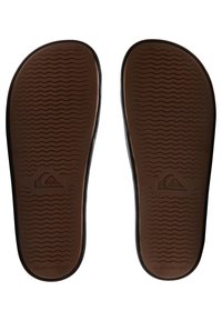 Sorte flip-flops med en brun tekstureret sål, der har et bølget mønster og et logo. Minimalistisk design med en glat finish omkring kanterne.