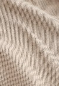 Beežikangas väikeste, kõrgendatud ruudukujuliste vahvlite tekstuuriga ja õrnad voldid, mis loovad pinna peale pehmeid varje.