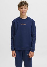 Navy blue cotton sweatshirt with crew neck, ribbed cuffs, and waistband. Features "Original Studio" embroidered in gold on the chest.