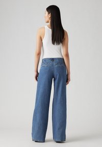Kõrge vöökoht ja lai sääre lõige helesinises denims, millel on veidi kulunud viimistlus. Omab tagataskuid ja kontrastset nööpimist.