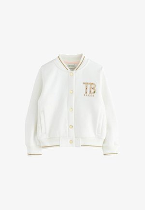 Hvid bomberjakke lavet af blødt stof med ribstrikkede manchetter og kant, der har guldfarvet hardware, broderet "TB BAKER" logo og sidelommer.