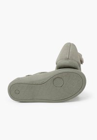 Grüner Wildlederschuh mit einem geschwungenen Rücken, strukturiertem Sohle und einem verstellbaren Riemen. Die Sohle hat ein strukturiertes Profil für besseren Halt.