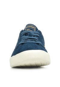 Baskets en daim bleu avec semelle en caoutchouc blanc, tige texturée et étiquette logo contrastante sur la languette. Lacets plats et design de bout renforcé.